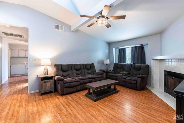 living room with lofted ceiling with beams, visible vents, light wood-style flooring, and a fireplace