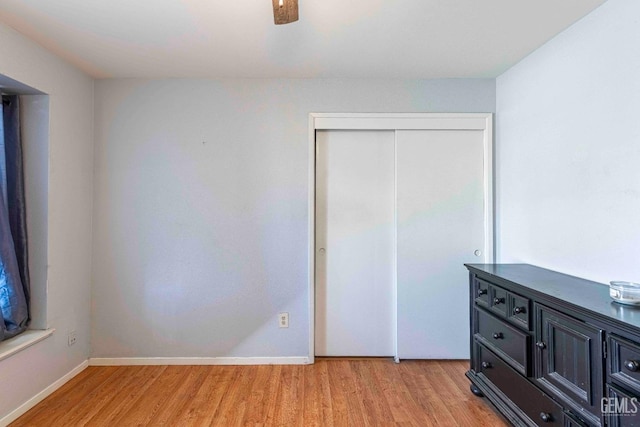 unfurnished bedroom featuring a closet, a ceiling fan, light wood-type flooring, and baseboards