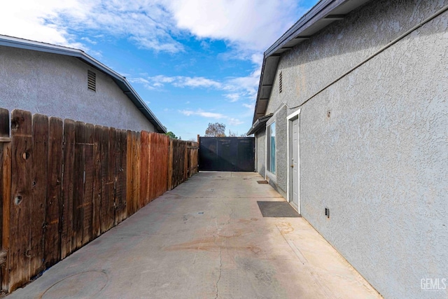 view of side of home with stucco siding, a patio, and fence