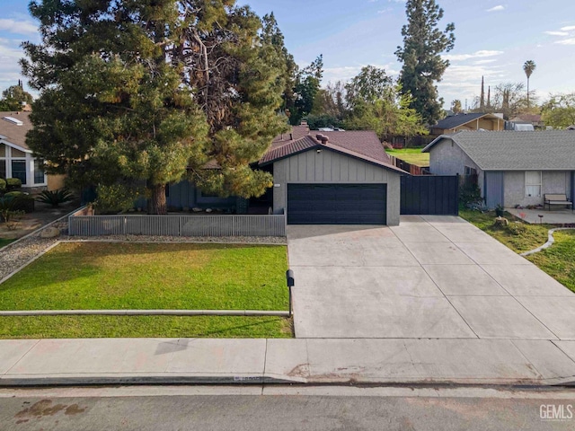 view of front of home with a front yard, fence, an attached garage, concrete driveway, and board and batten siding