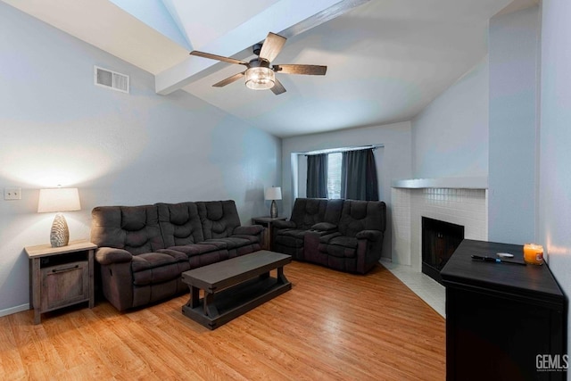 living area featuring light wood-type flooring, visible vents, a brick fireplace, ceiling fan, and vaulted ceiling