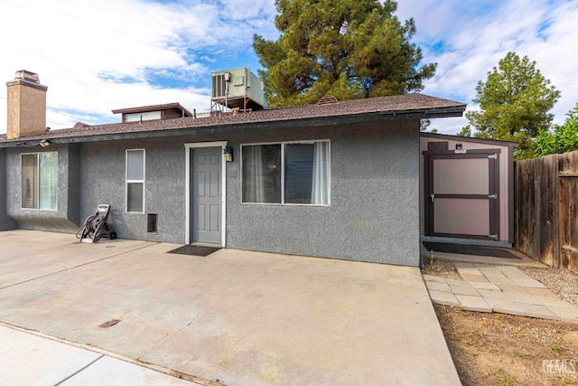 back of property with a patio, fence, central AC, and stucco siding