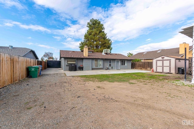 rear view of property featuring a patio, an outbuilding, a fenced backyard, a chimney, and a storage unit