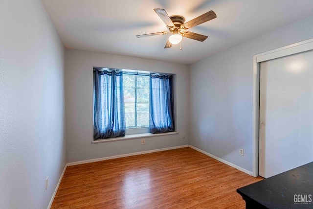 spare room featuring baseboards, light wood-style floors, and a ceiling fan