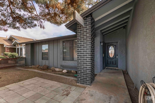 view of exterior entry with stucco siding and board and batten siding