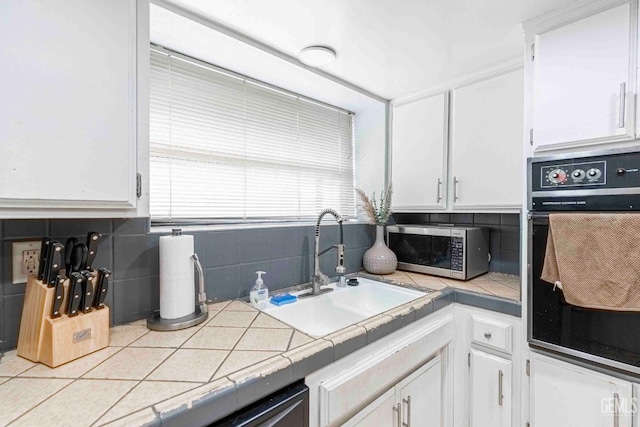 kitchen featuring decorative backsplash, stainless steel microwave, white cabinets, and oven