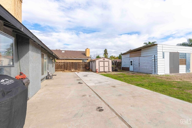 view of patio featuring a storage unit, a fenced backyard, and an outdoor structure