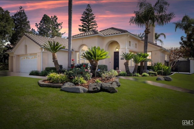 mediterranean / spanish house featuring a garage and a yard