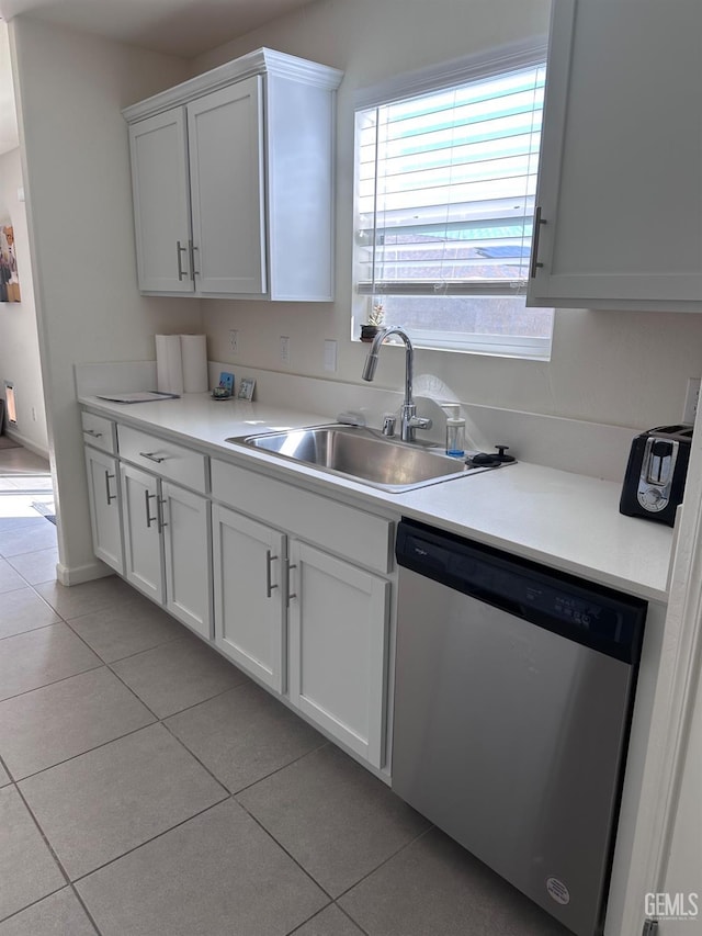 kitchen with light tile patterned floors, light countertops, white cabinets, a sink, and dishwasher