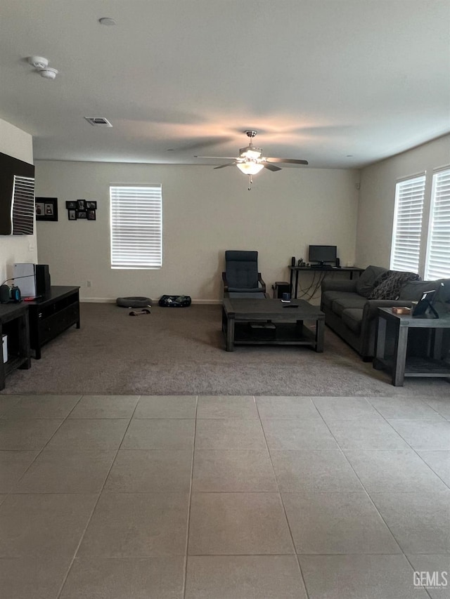 carpeted living room featuring a ceiling fan, visible vents, and tile patterned floors