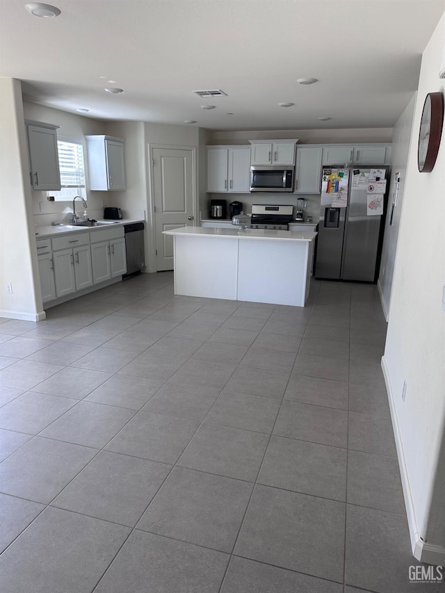 kitchen featuring baseboards, appliances with stainless steel finishes, light countertops, a sink, and light tile patterned flooring