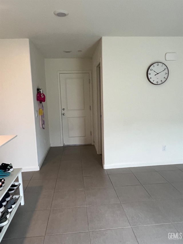 hall featuring light tile patterned floors and baseboards