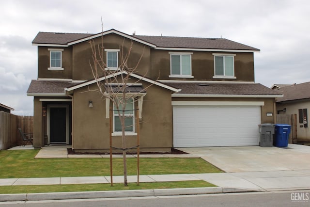 traditional-style home with a garage, fence, concrete driveway, and stucco siding