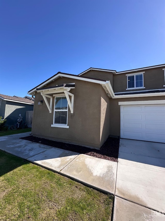 view of front of property with a garage, concrete driveway, and stucco siding