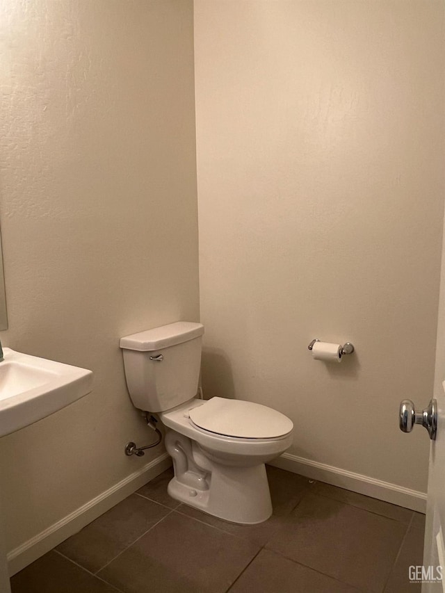 half bathroom featuring toilet, tile patterned flooring, and baseboards