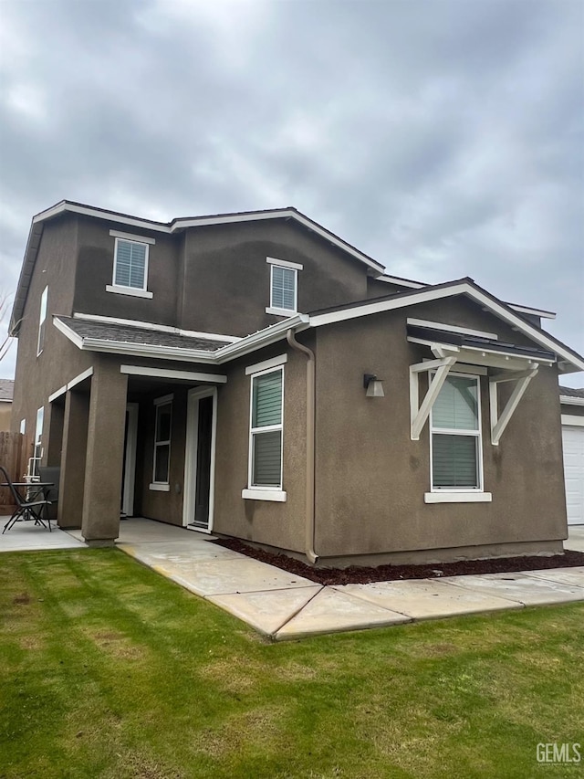 rear view of property featuring a patio area, a yard, and stucco siding