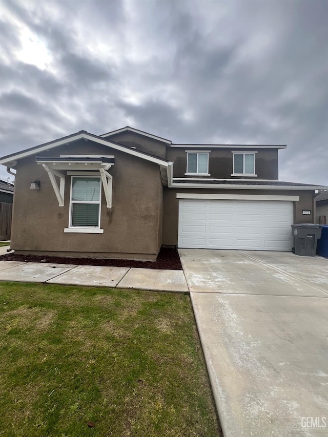 view of front facade with a garage, driveway, a front yard, and stucco siding