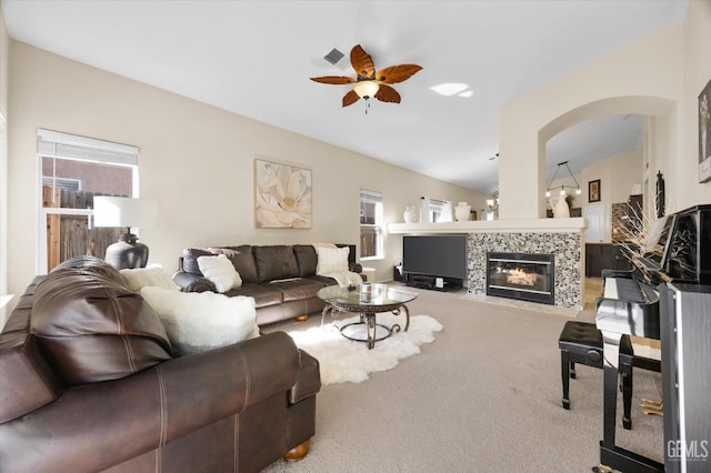 living room featuring vaulted ceiling, ceiling fan, carpet floors, and a tile fireplace