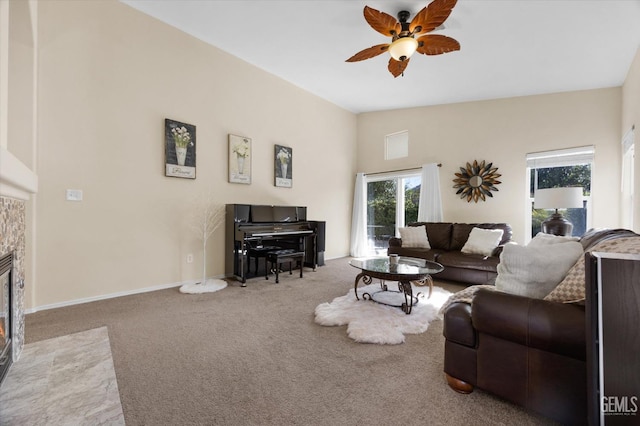 living room with vaulted ceiling, ceiling fan, a tiled fireplace, and carpet floors