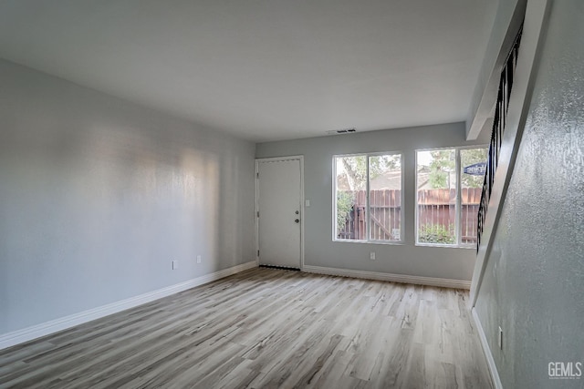 empty room featuring visible vents, baseboards, and wood finished floors