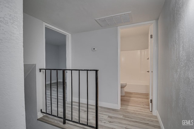 corridor with wood finished floors, visible vents, and baseboards