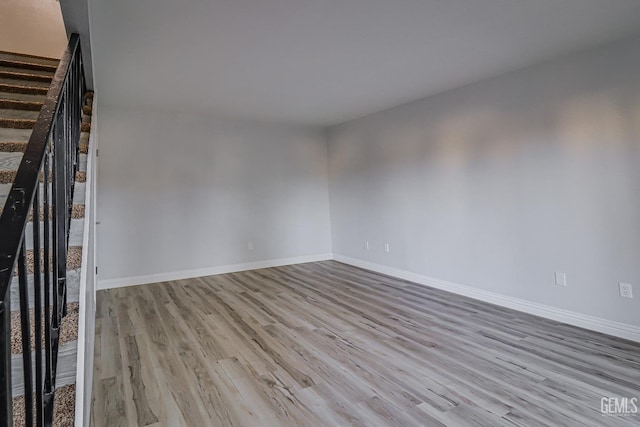 spare room featuring stairs, baseboards, and wood finished floors