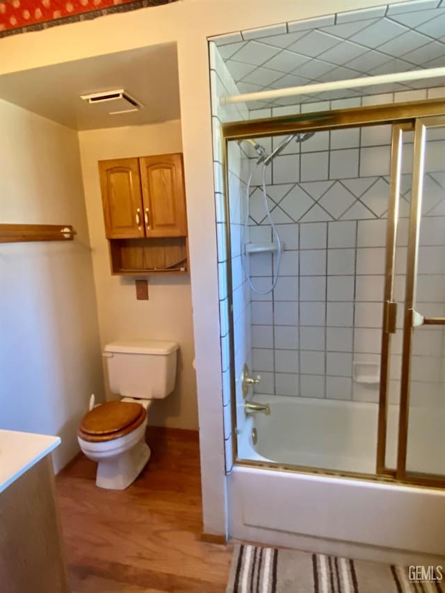 full bathroom with bath / shower combo with glass door, toilet, vanity, and hardwood / wood-style floors