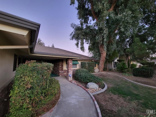 6918 Crestwood St, Bakersfield, CA 93308 - exterior entry at dusk featuring a lawn