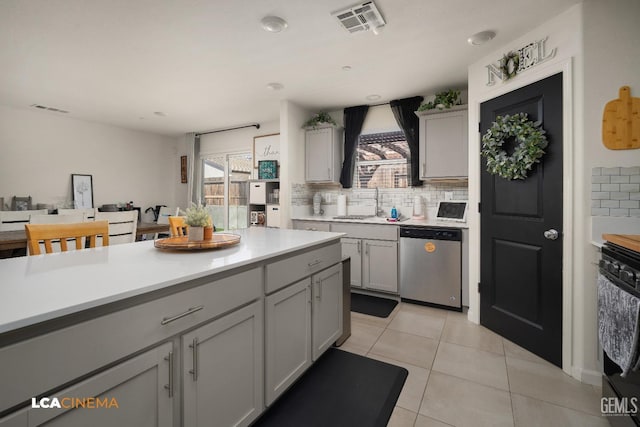 kitchen featuring gray cabinetry, sink, tasteful backsplash, stainless steel dishwasher, and light tile patterned flooring