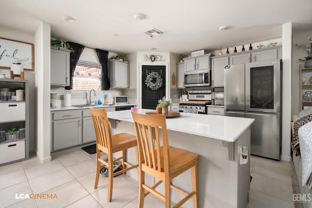 kitchen with a kitchen bar, stainless steel appliances, and gray cabinets