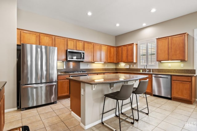 5703 Park Pl, Bakersfield, CA 93306 - kitchen with appliances with stainless steel finishes, brown cabinets, a center island, a kitchen breakfast bar, and recessed lighting