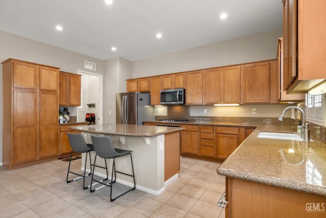 5703 Park Pl, Bakersfield, CA 93306 - kitchen featuring a kitchen bar, light stone counters, appliances with stainless steel finishes, recessed lighting, and a kitchen island