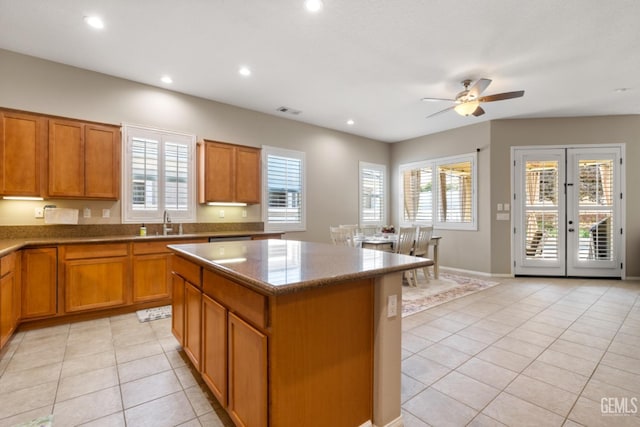 5703 Park Pl, Bakersfield, CA 93306 - kitchen with light tile patterned flooring, brown cabinetry, a center island, ceiling fan, and healthy amount of natural light