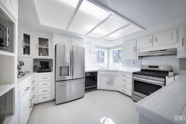 kitchen with appliances with stainless steel finishes, tile countertops, sink, and white cabinets