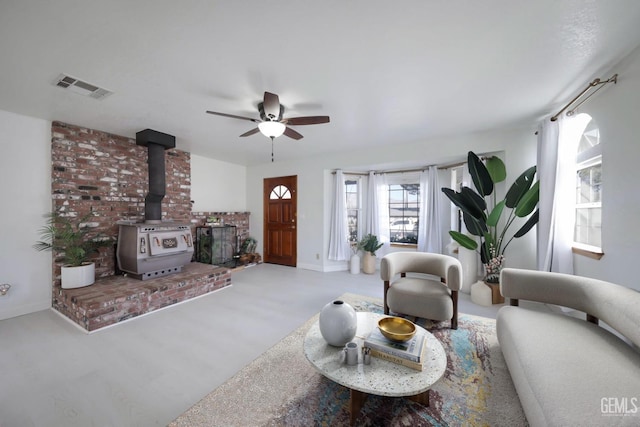 living room with hardwood / wood-style flooring, ceiling fan, and a wood stove