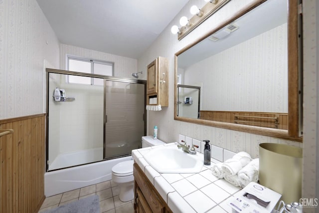 full bathroom featuring vanity, bath / shower combo with glass door, tile patterned floors, and toilet