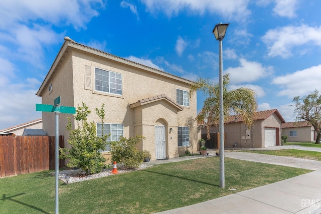 mediterranean / spanish home featuring a front yard, fence, an attached garage, and stucco siding