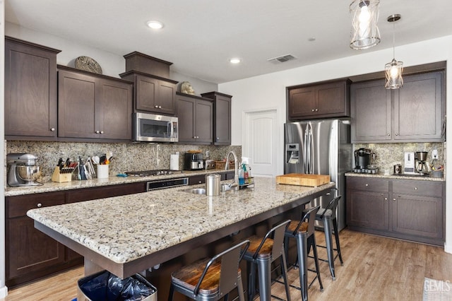 kitchen featuring dark brown cabinets, visible vents, tasteful backsplash, and appliances with stainless steel finishes