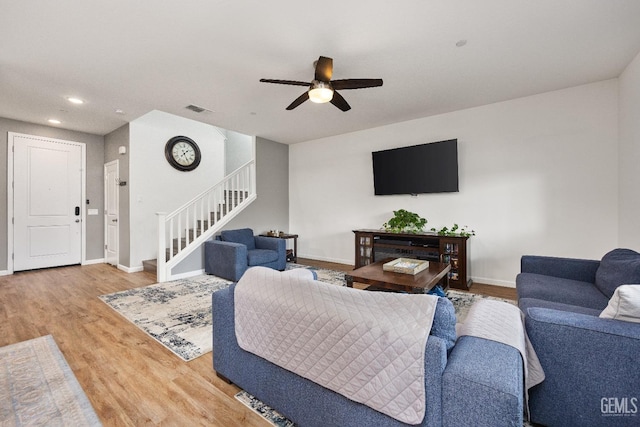 living area featuring stairway, baseboards, visible vents, and wood finished floors