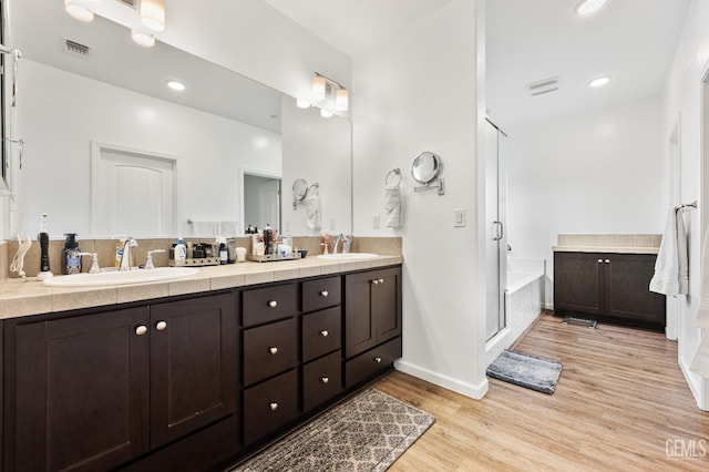 bathroom with double vanity, wood finished floors, visible vents, and a sink