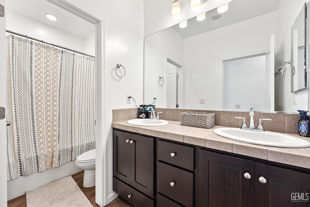 bathroom with double vanity, curtained shower, toilet, and a sink