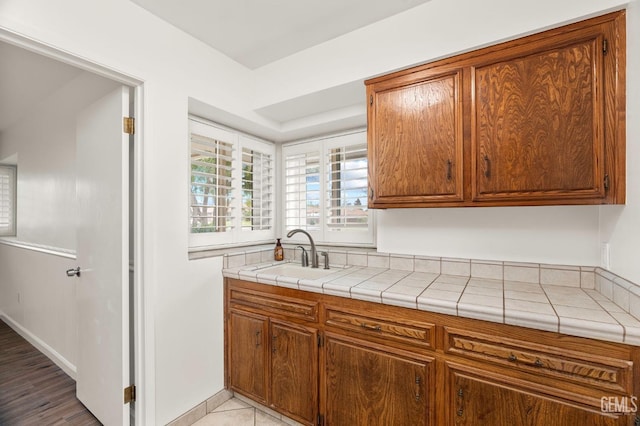 kitchen with baseboards, brown cabinets, and a sink