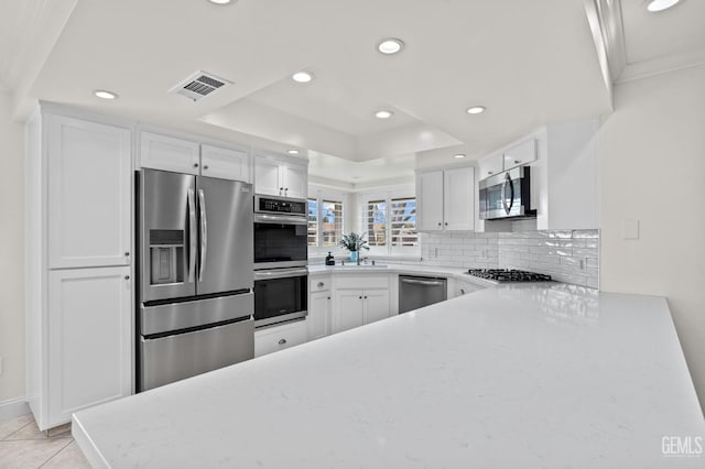 kitchen with stainless steel appliances, a raised ceiling, visible vents, and white cabinets