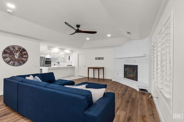 living area with recessed lighting, wood finished floors, visible vents, a ceiling fan, and a brick fireplace