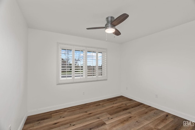 spare room with wood finished floors, a ceiling fan, and baseboards