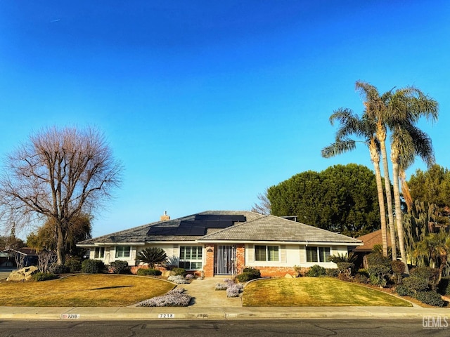 ranch-style home featuring a front yard and solar panels