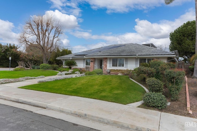 ranch-style home with solar panels, a front lawn, and brick siding