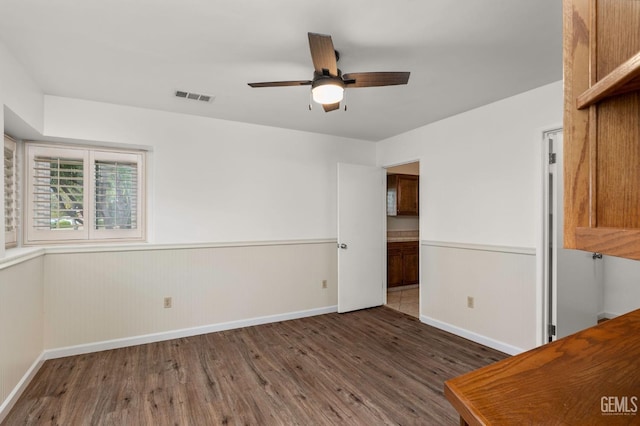 interior space featuring visible vents, wainscoting, ceiling fan, wood finished floors, and baseboards