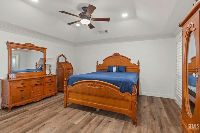 bedroom featuring a raised ceiling, visible vents, ornamental molding, light wood-type flooring, and baseboards