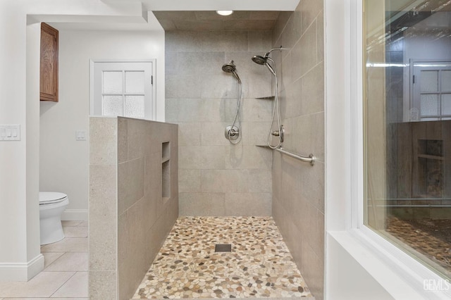 full bathroom featuring toilet, baseboards, tiled shower, and tile patterned floors